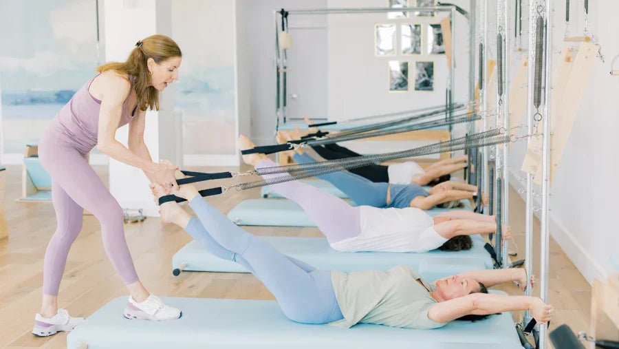 Pilates instructor teaching clients on Gratz Pilates Studio Wall Unit with High Mat