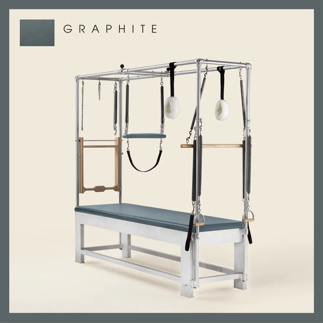 Graphite color Trapeze Table with aluminum frame, adjustable bars, straps, and springs. Premium Pilates equipment against a beige background.