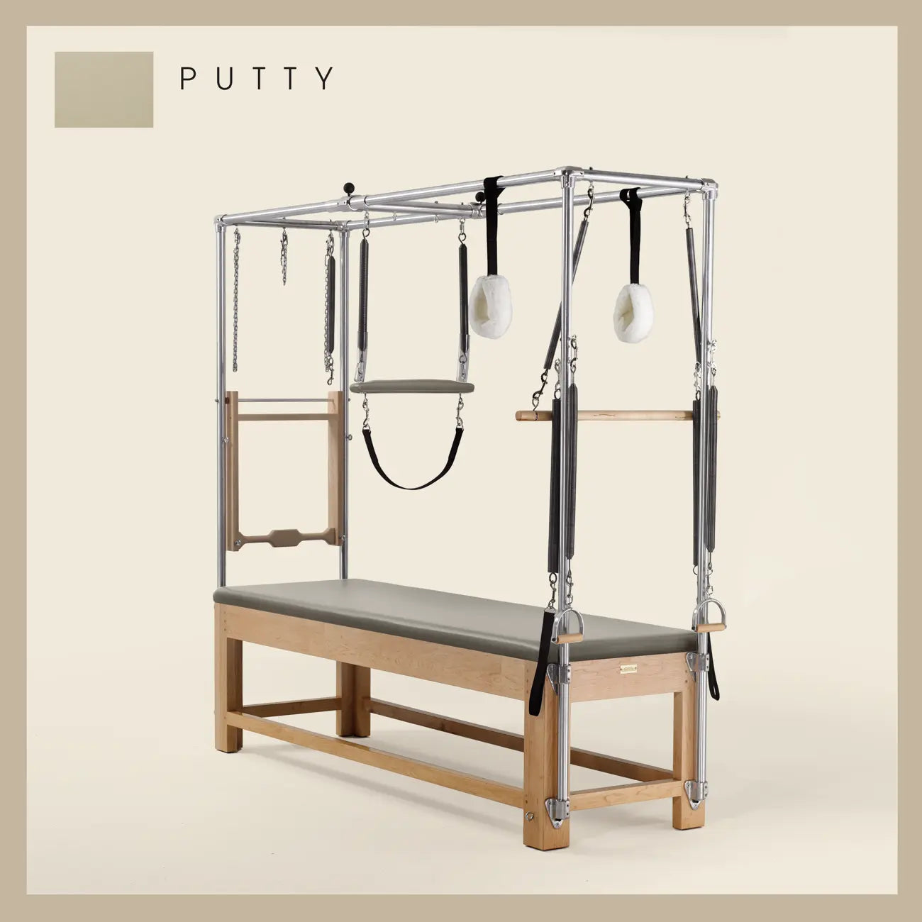 Putty color Pilates Cadillac with maple wood frame, adjustable bars, straps, and springs. Premium Pilates equipment against a beige background.