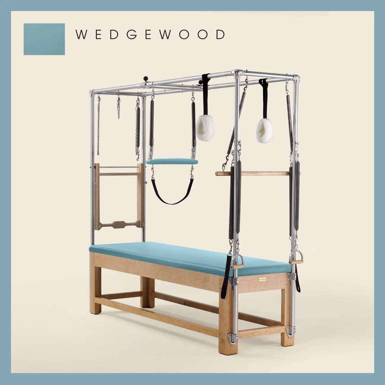 Wedgewood color Pilates Cadillac with maple wood frame, adjustable bars, straps, and springs. Premium Pilates equipment against a beige background.