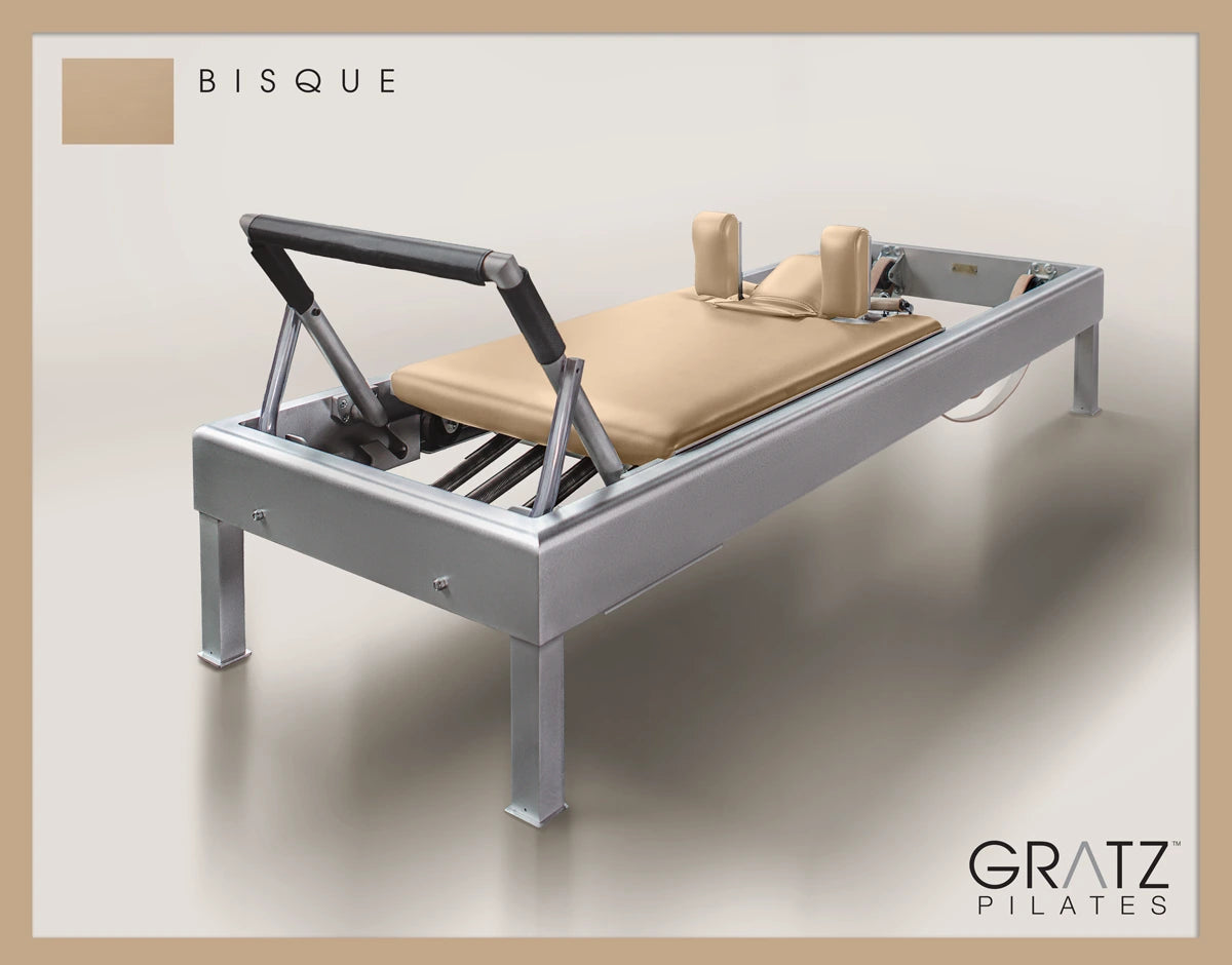 Gratz Pilates Aluminum Archive Reformer Equipment in Bisque color Padded Carriage. Soft beige background.