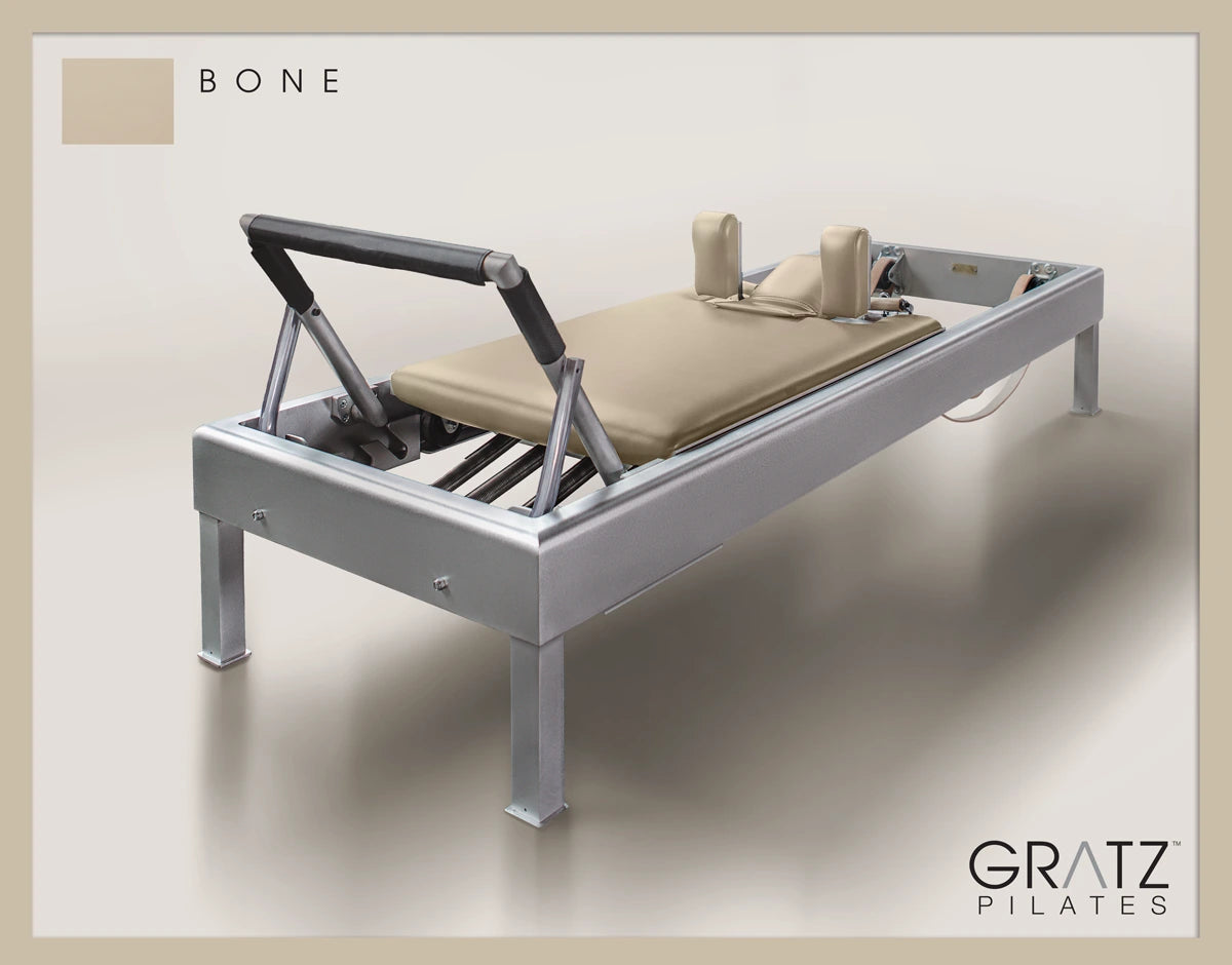 Gratz Pilates Aluminum Archive Reformer Equipment in Bone color Padded Carriage.  Soft beige background.