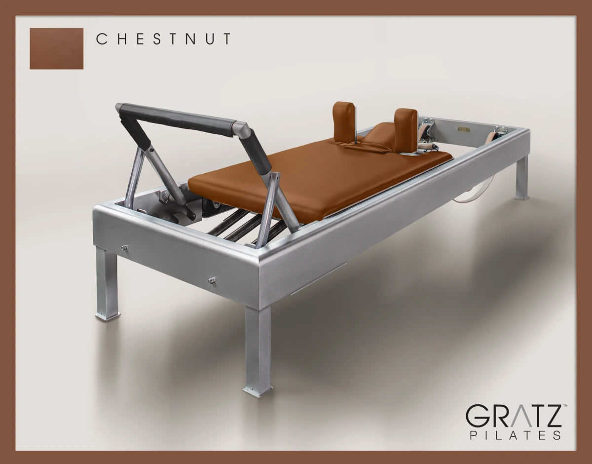 Gratz Pilates Aluminum Archive Reformer Equipment in Chestnut color Padded Carriage.  Soft beige background.