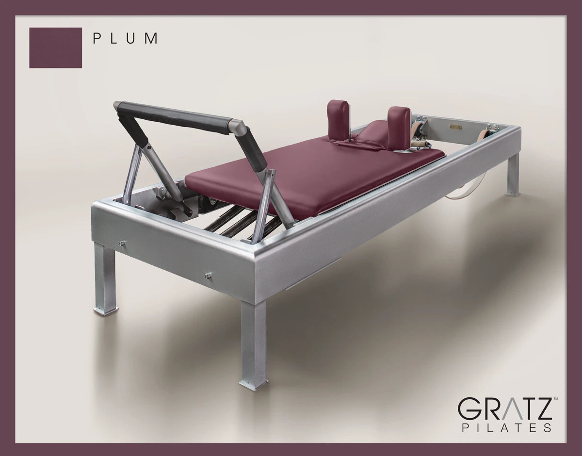 Gratz Pilates Aluminum Archive Reformer Equipment in Plum color Padded Carriage.  Soft beige background.