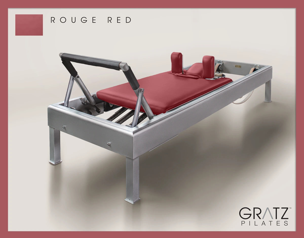 Gratz Pilates Aluminum Archive Reformer Equipment in Rouge Red color Padded Carriage. Soft beige background.