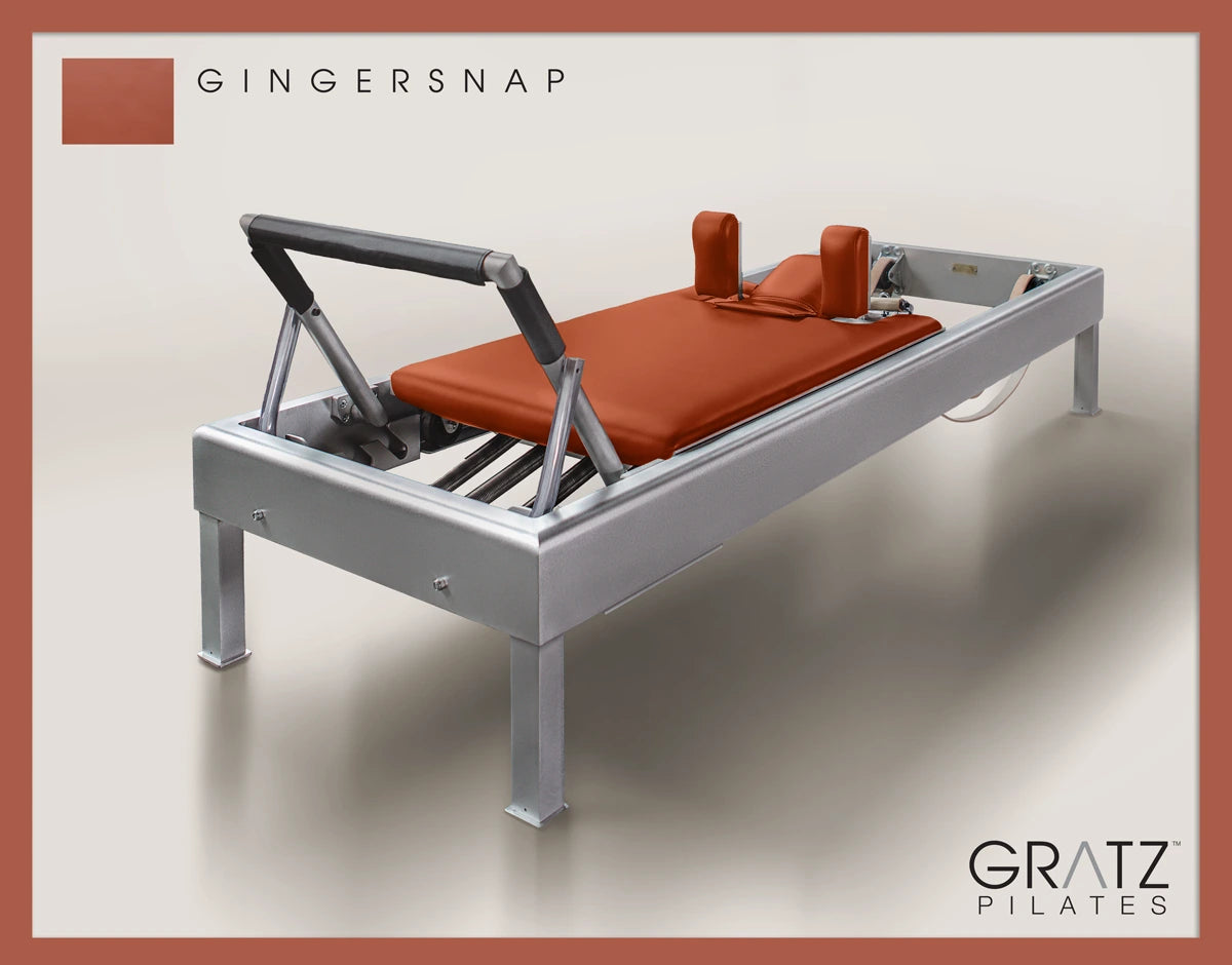 Gratz Pilates Aluminum Archive Reformer Equipment in Gingersnap color Padded Carriage.  Soft beige background.