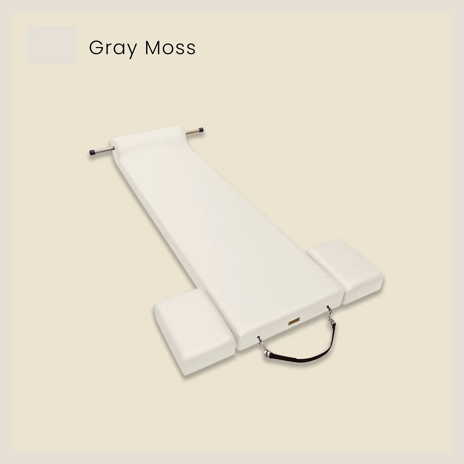 Gray pilates mat in with foot strap and side cushions on a light beige background.