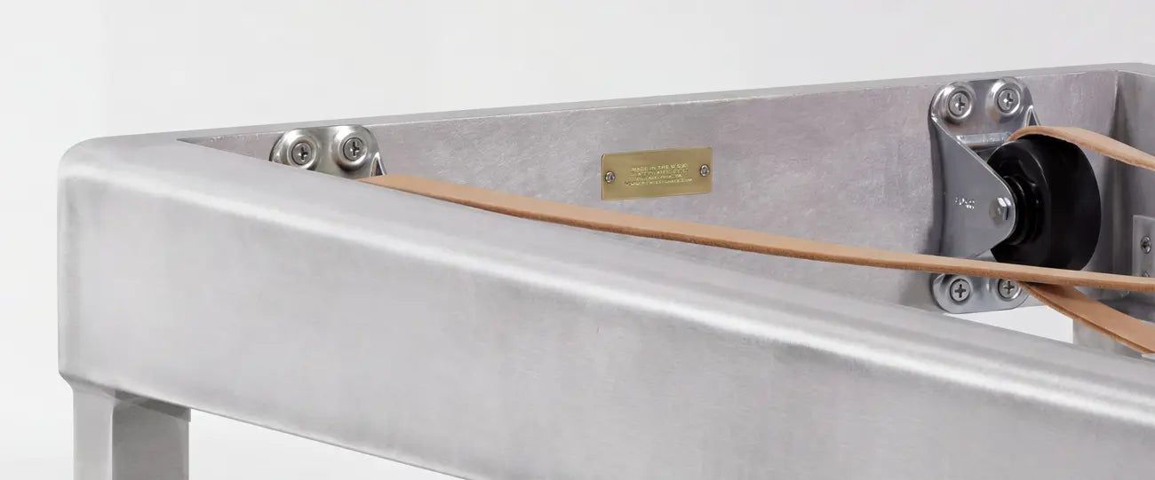 Gray Pilates reformer machine with padded carriage and spring resistance system on white background