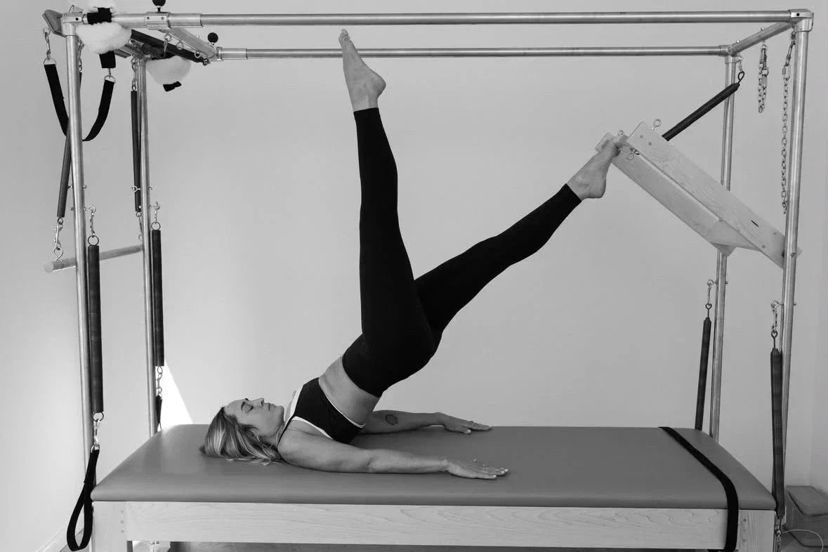 Person lying on a Cadillac performing Pilates using the Push Thru Bar