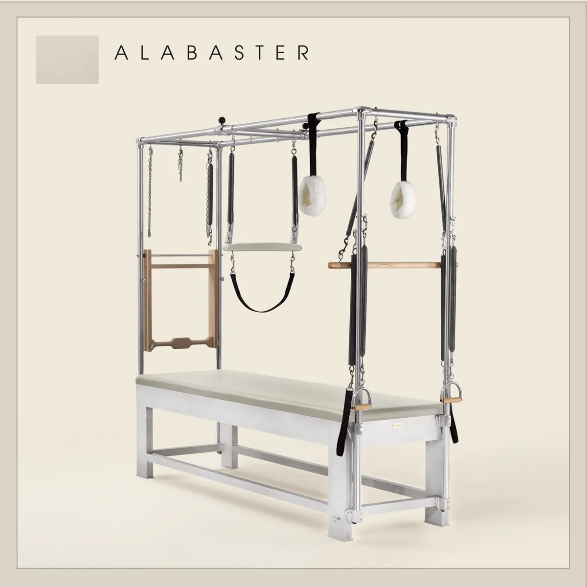 Alabaster color Trapeze Table with aluminum frame, adjustable bars, straps, and springs. Premium Pilates equipment against a beige background.