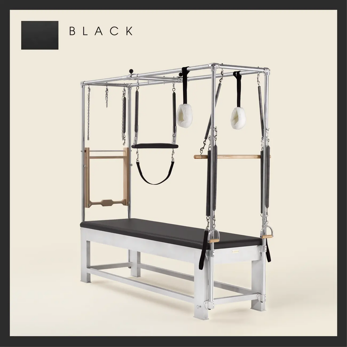Black color Trapeze Table with aluminum frame, adjustable bars, straps, and springs. Premium Pilates equipment against a beige background.