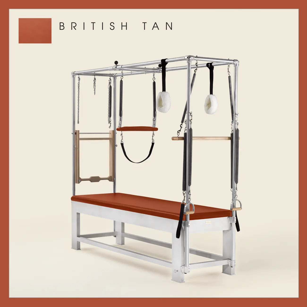 British Tan color Trapeze Table with aluminum frame, adjustable bars, straps, and springs. Premium Pilates equipment against a beige background.