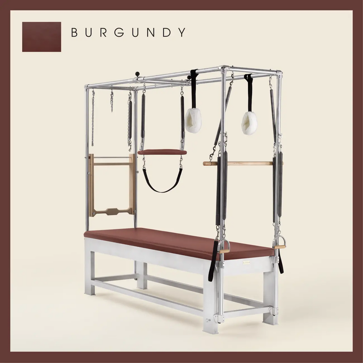 Burgundy color Trapeze Table with aluminum frame, adjustable bars, straps, and springs. Premium Pilates equipment against a beige background.