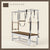 Espresso color Trapeze Table with aluminum frame, adjustable bars, straps, and springs. Premium Pilates equipment against a beige background.