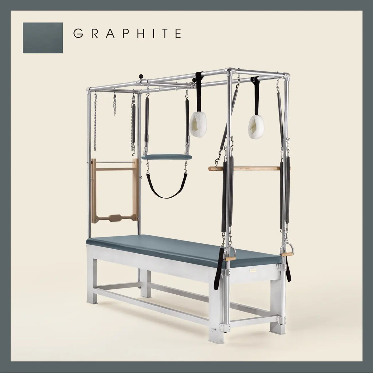 Graphite color Trapeze Table with aluminum frame, adjustable bars, straps, and springs. Premium Pilates equipment against a beige background.