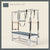 Graphite color Trapeze Table with aluminum frame, adjustable bars, straps, and springs. Premium Pilates equipment against a beige background.