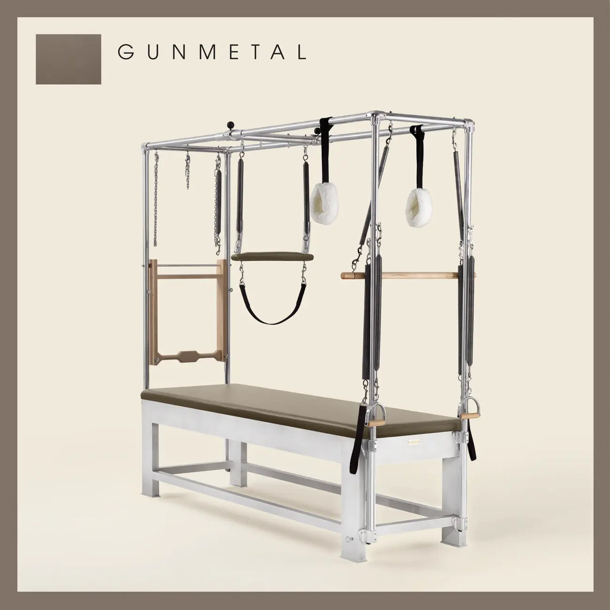 Gunmetal color Trapeze Table with aluminum frame, adjustable bars, straps, and springs. Premium Pilates equipment against a beige background.