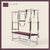 Plum color Trapeze Table with aluminum frame, adjustable bars, straps, and springs. Premium Pilates equipment against a beige background.