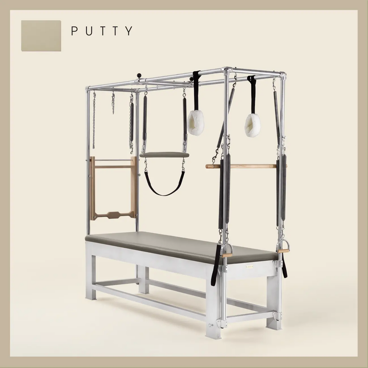 Putty color Trapeze Table with aluminum frame, adjustable bars, straps, and springs. Premium Pilates equipment against a beige background.