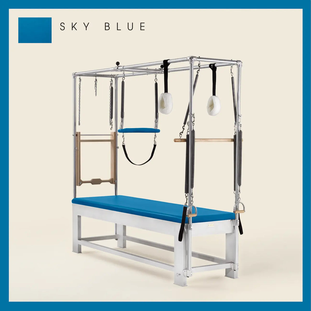 Sky blue color Trapeze Table with aluminum frame, adjustable bars, straps, and springs. Premium Pilates equipment against a beige background.