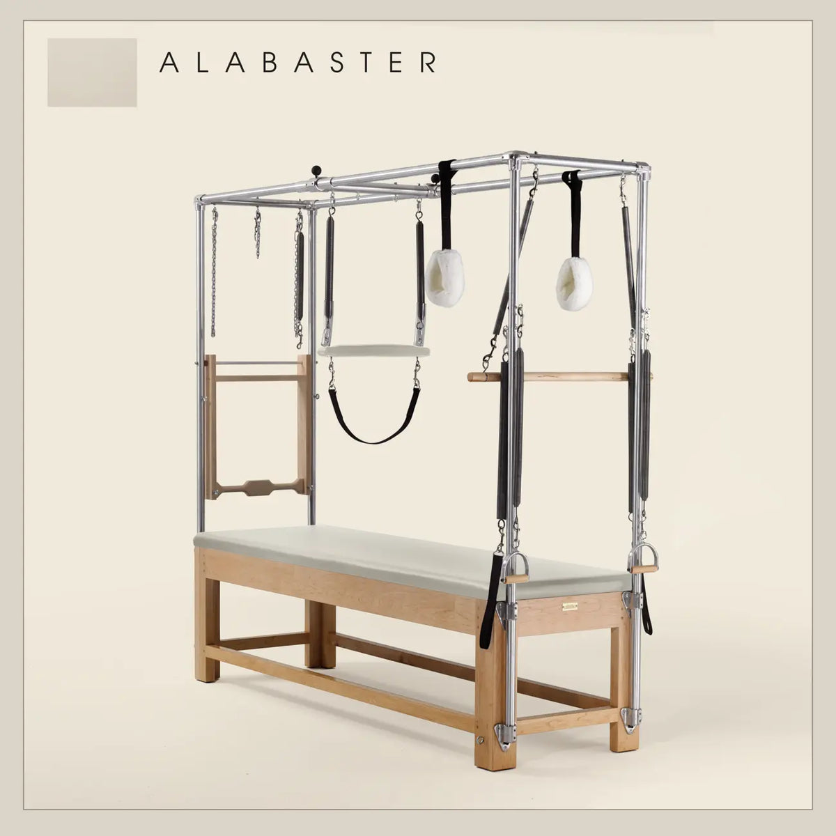 Alabaster color Pilates Cadillac with maple wood frame, adjustable bars, straps, and springs. Premium Pilates equipment against a beige background.