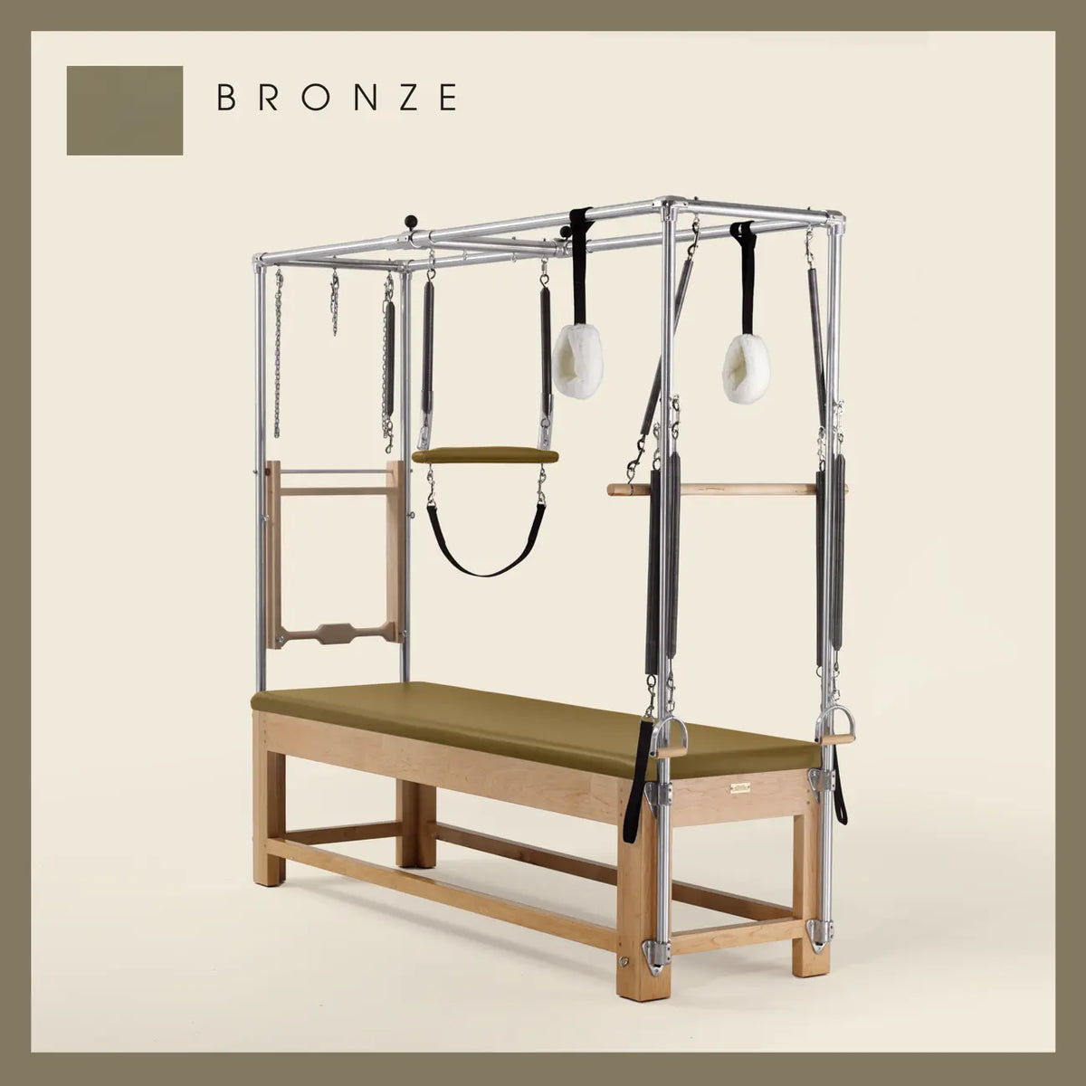 Bronze color Pilates Cadillac with maple wood frame, adjustable bars, straps, and springs. Premium Pilates equipment against a beige background.