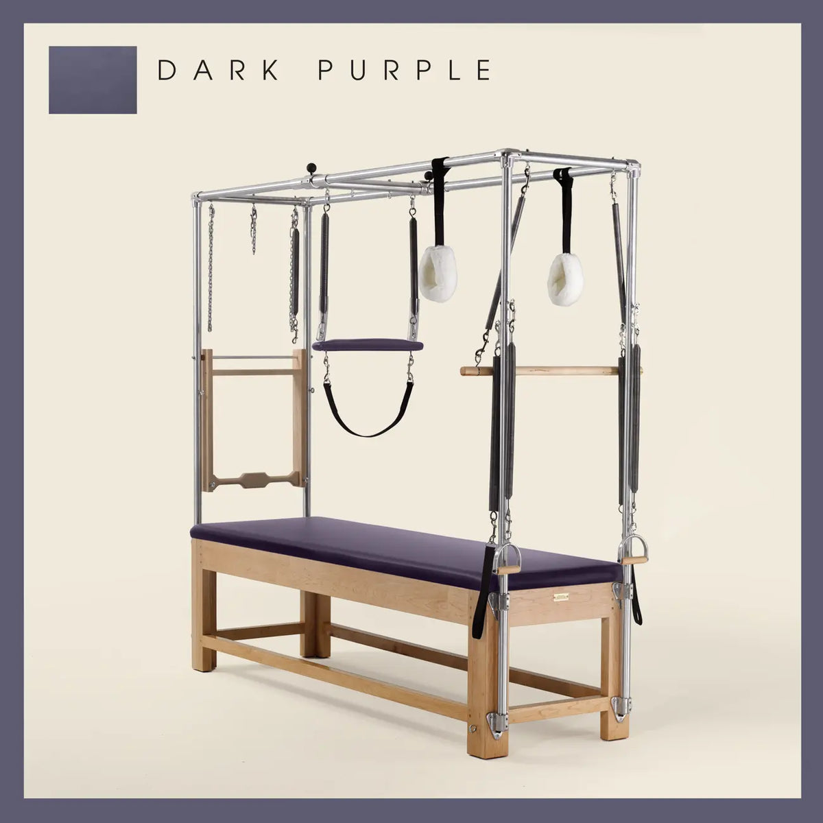 Dark Purple Pilates Cadillac with maple wood frame, adjustable bars, straps, and springs. Premium Pilates equipment against a beige background.