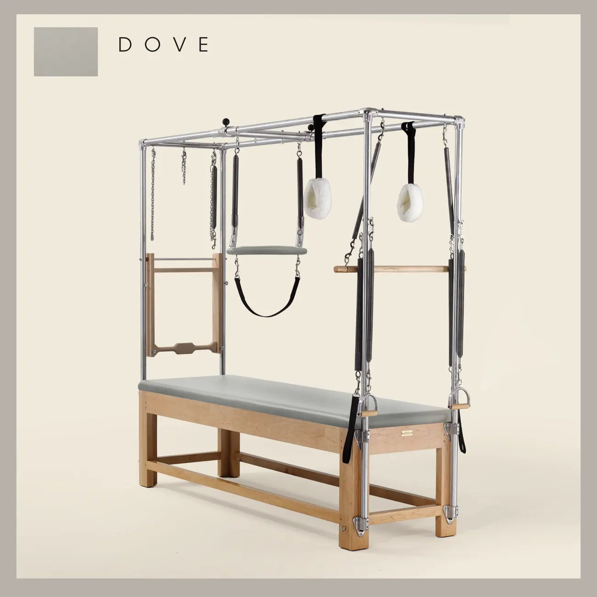 Dove color Pilates Cadillac with maple wood frame, adjustable bars, straps, and springs. Premium Pilates equipment against a beige background.