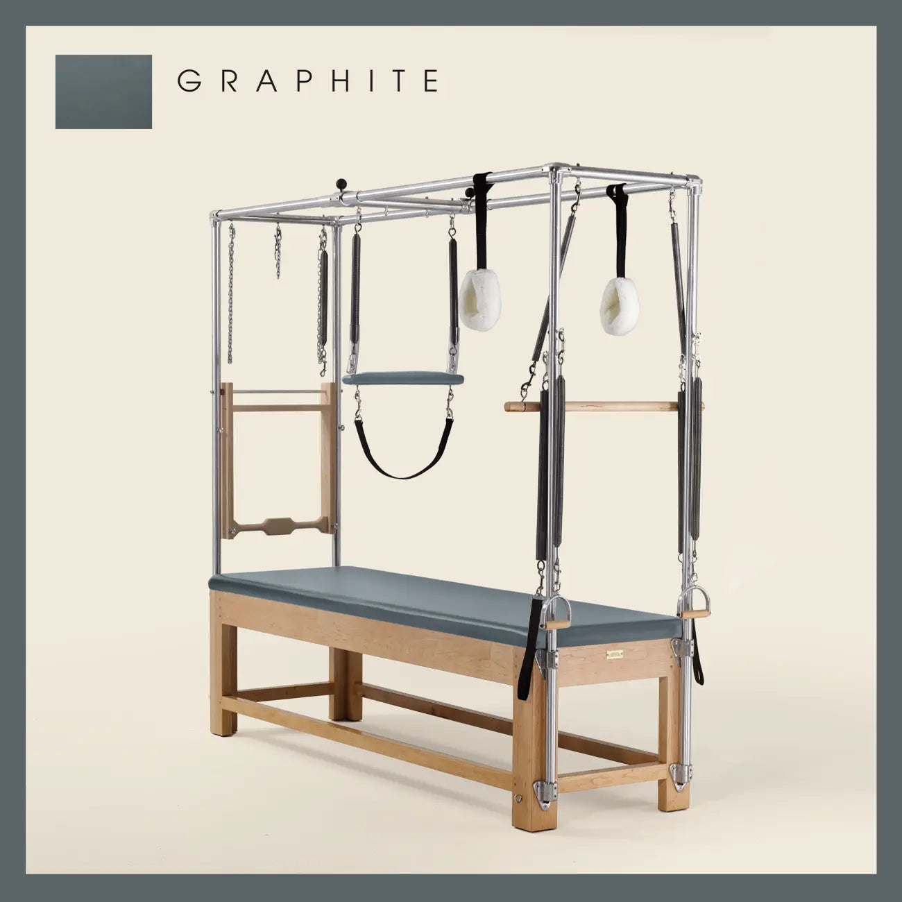 Graphite color Pilates Cadillac with maple wood frame, adjustable bars, straps, and springs. Premium Pilates equipment against a beige background.
