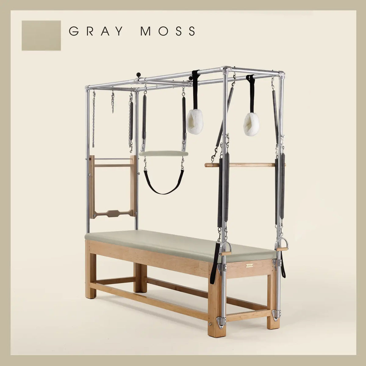 Gray moss color Pilates Cadillac with maple wood frame, adjustable bars, straps, and springs. Premium Pilates equipment against a beige background.