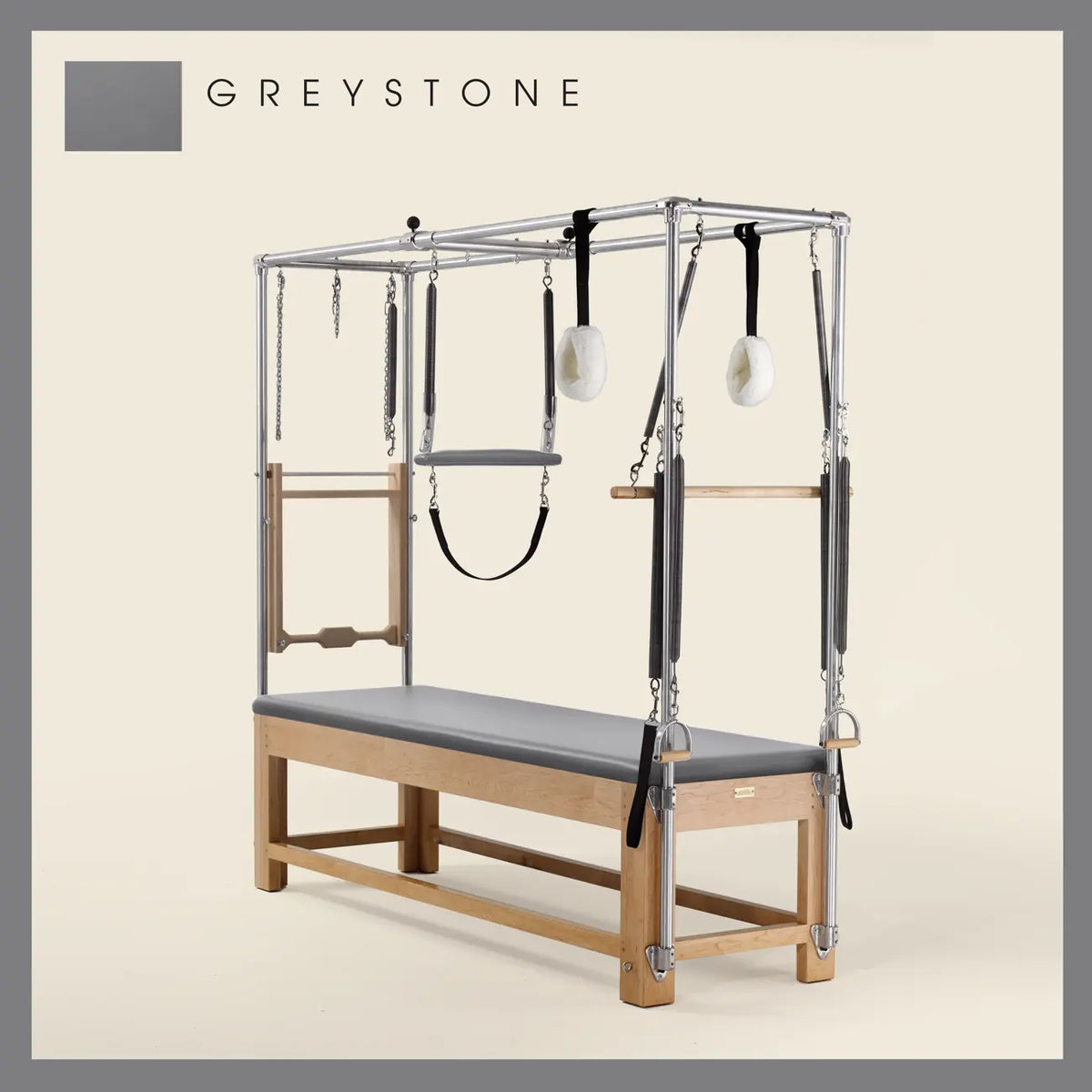 Greystone Pilates Cadillac with maple wood frame, adjustable bars, straps, and springs. Premium Pilates equipment against a beige background.