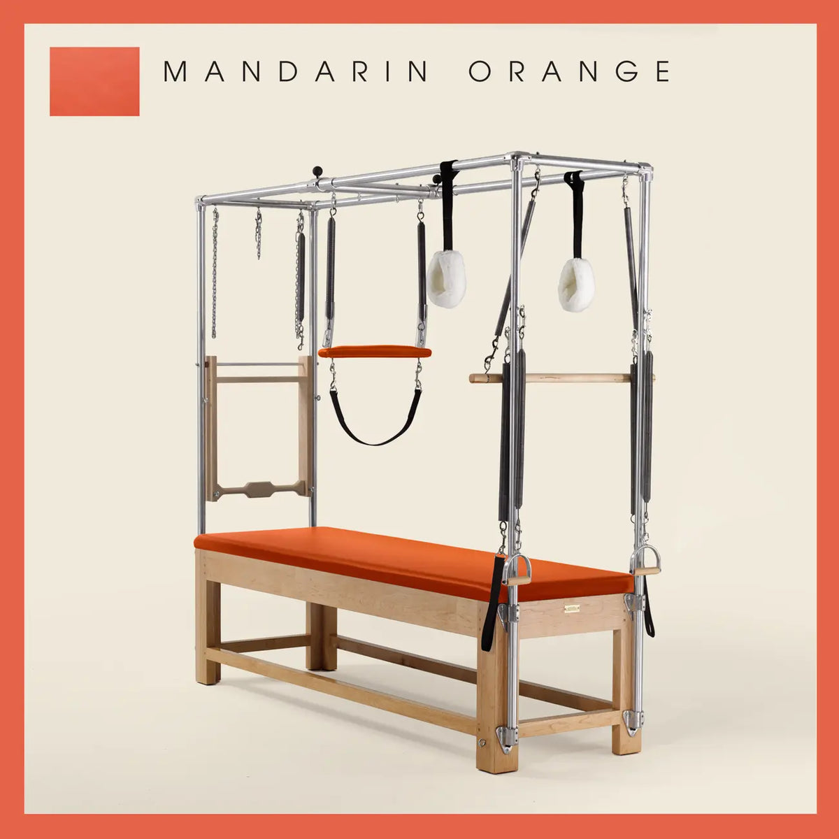 Mandarin Orange Pilates Cadillac with maple wood frame, adjustable bars, straps, and springs. Premium Pilates equipment against a beige background.