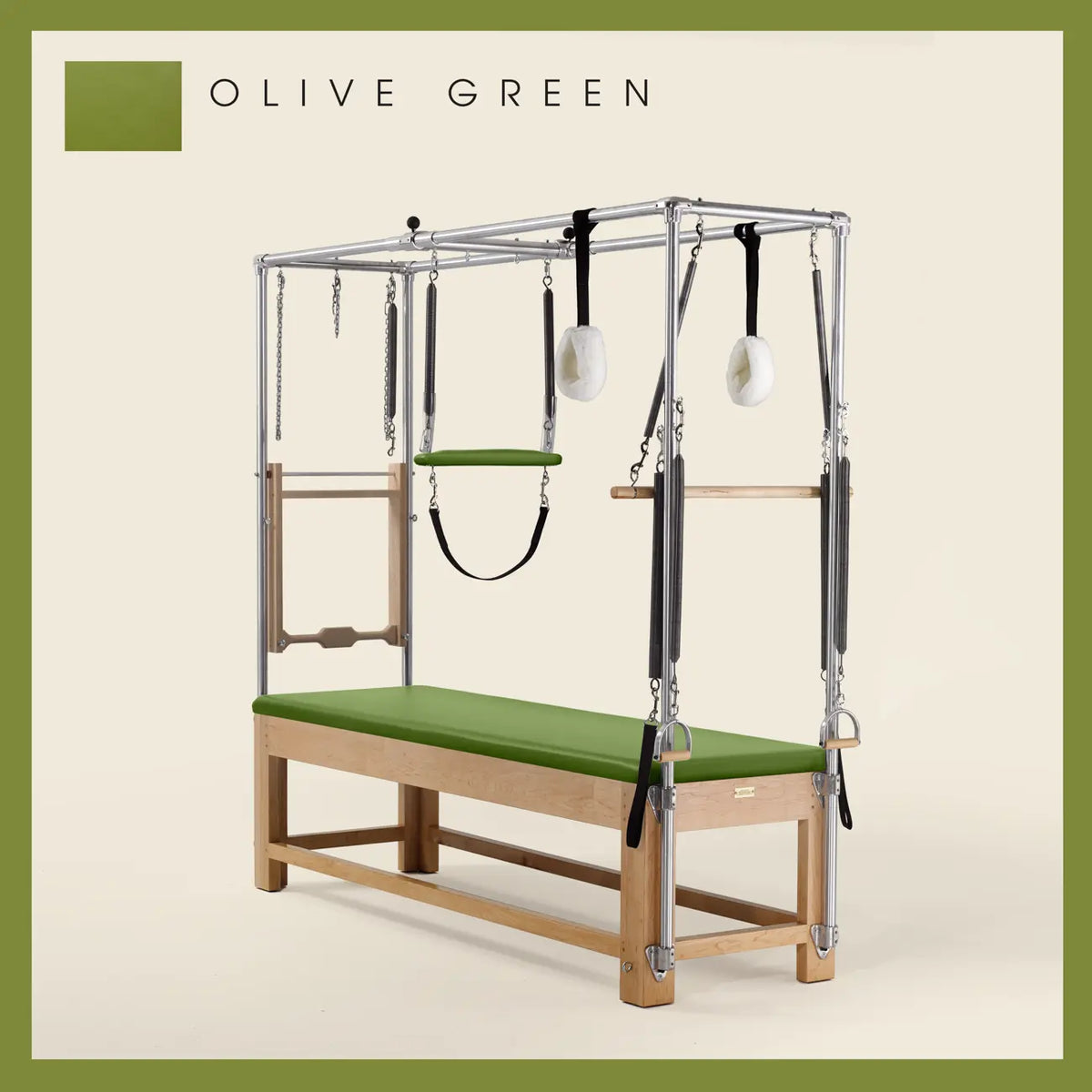 Olive Green Pilates Cadillac with maple wood frame, adjustable bars, straps, and springs. Premium Pilates equipment against a beige background.