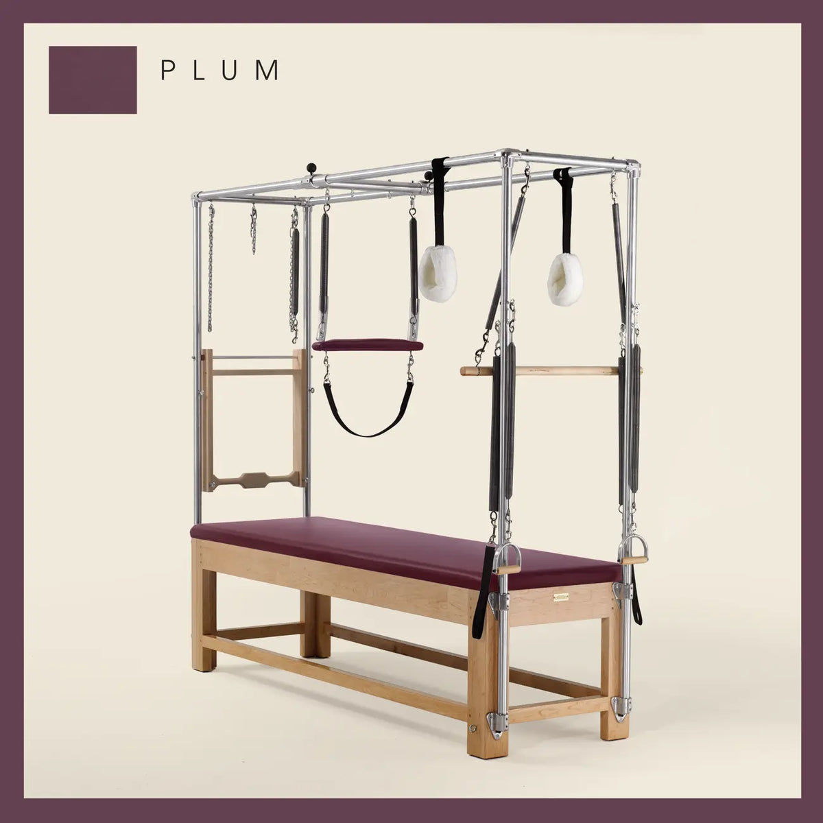 Plum color Pilates Cadillac with maple wood frame, adjustable bars, straps, and springs. Premium Pilates equipment against a beige background.