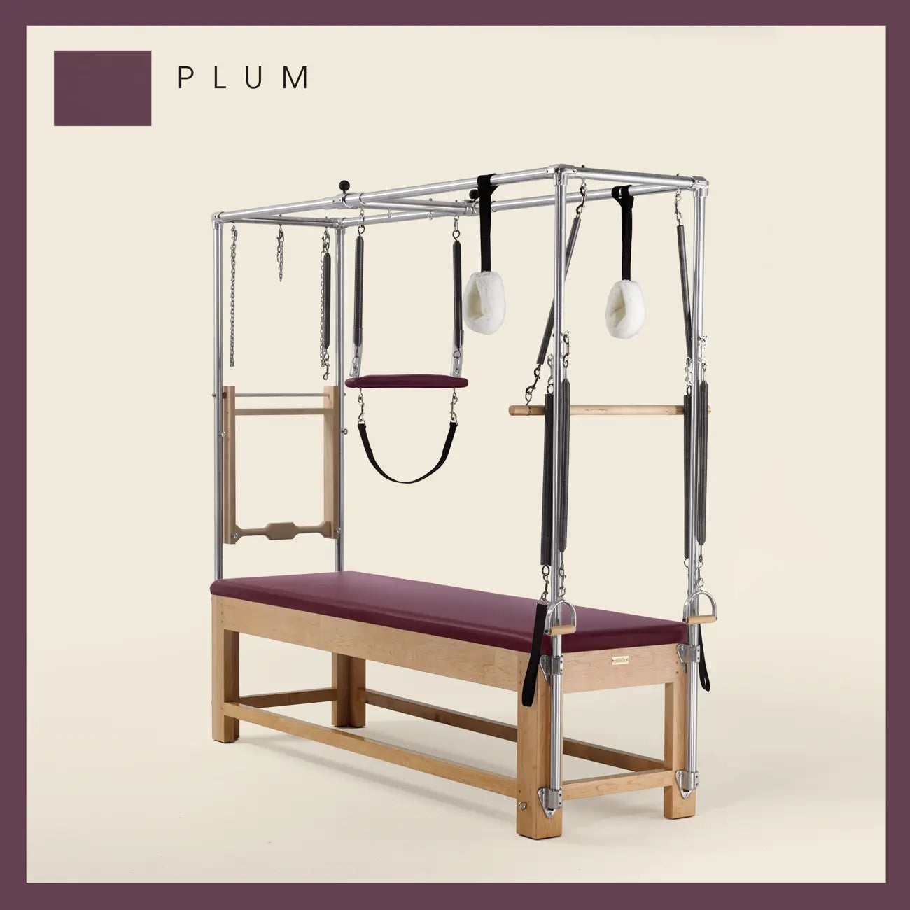 Plum color Pilates Cadillac with maple wood frame, adjustable bars, straps, and springs. Premium Pilates equipment against a beige background.