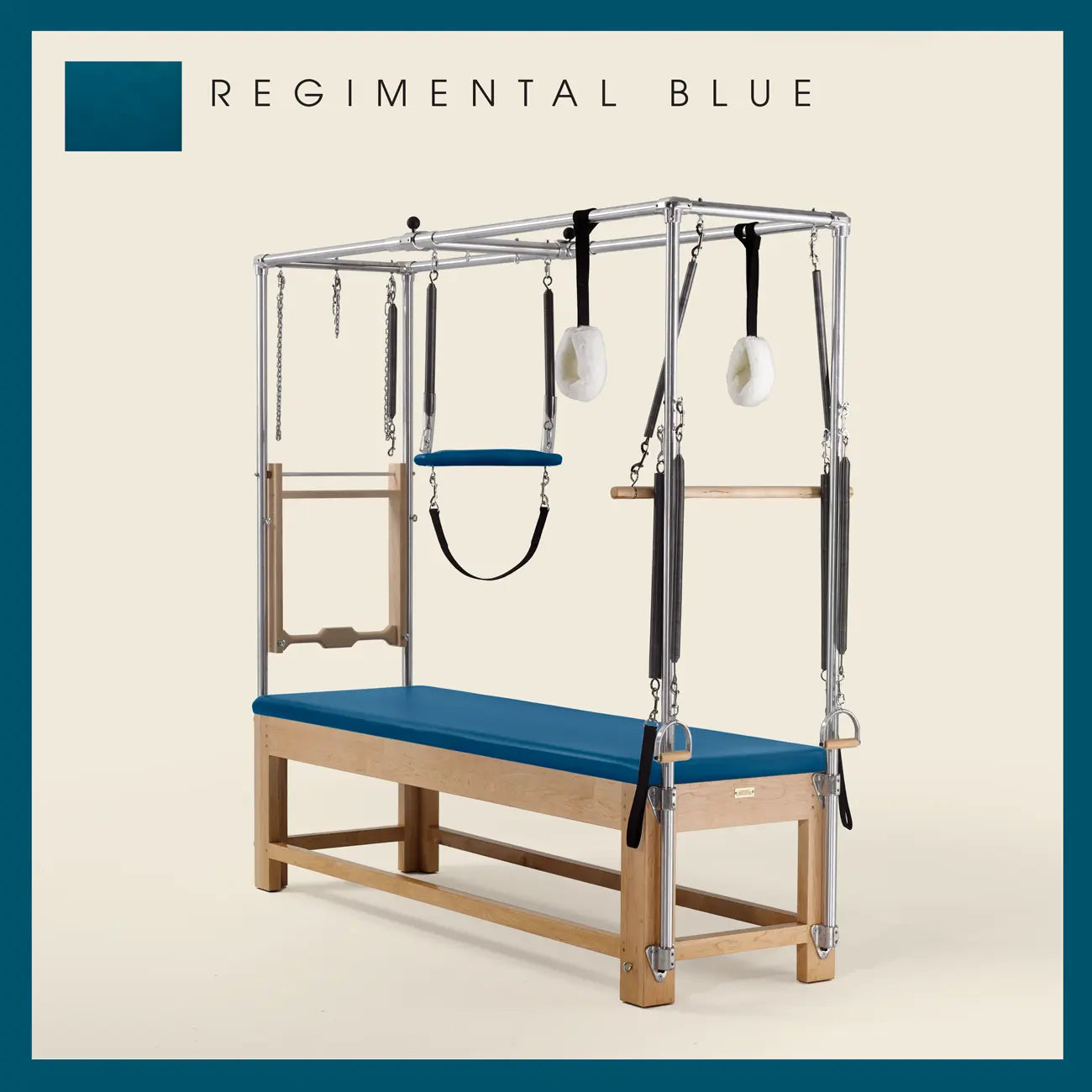 Regimental Blue Pilates Cadillac with maple wood frame, adjustable bars, straps, and springs. Premium Pilates equipment against a beige background.