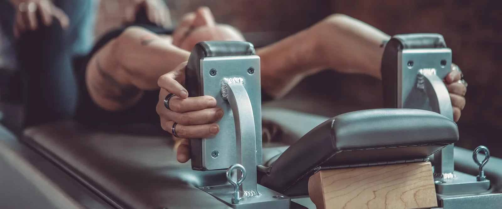 Closeup view of the Reformer Shoulder Blocks with woman's hand grabbing them