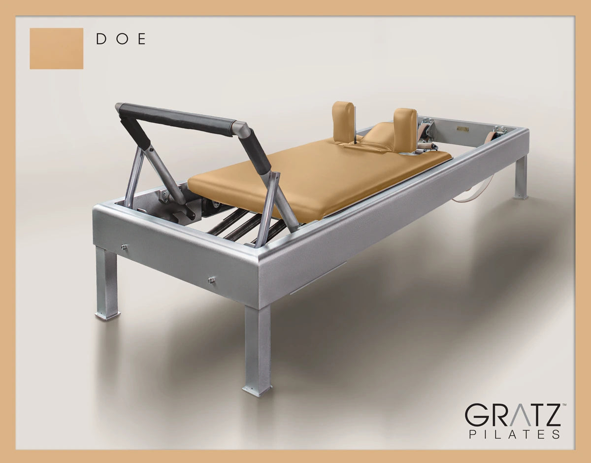Gratz Pilates Aluminum Archive Reformer Equipment in Doe color Padded Carriage.  Soft beige background. 