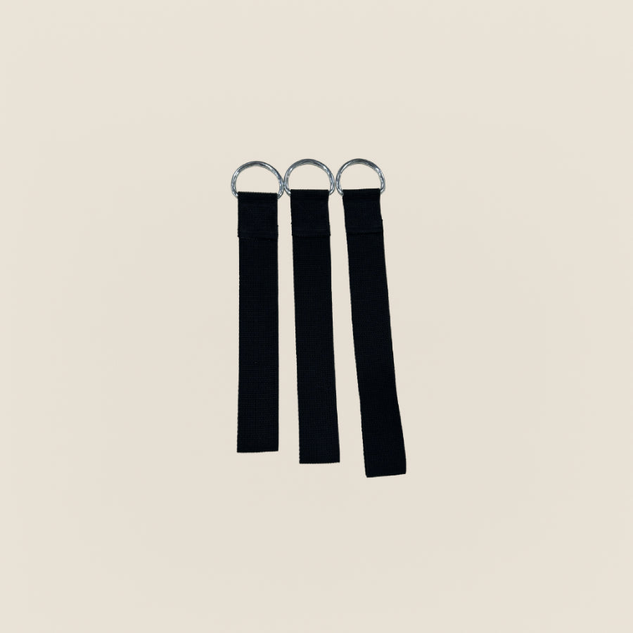 Three black Pilates neck stretcher straps with metal D-rings on a beige background.