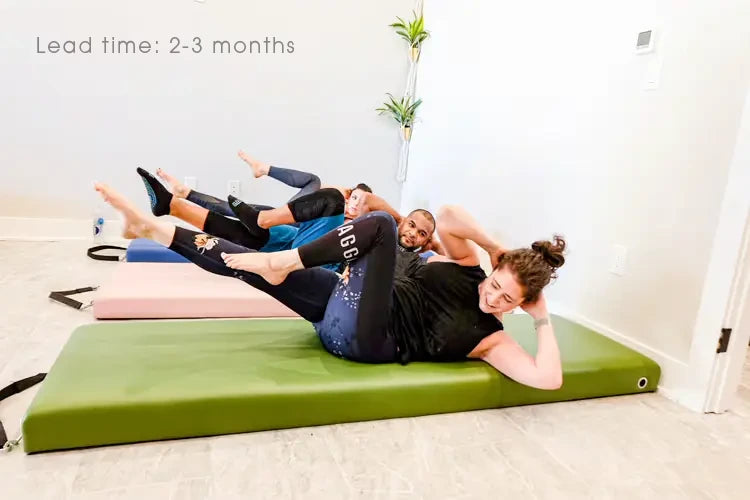 3 people exercising on multi-color Pilates Mats in a Pilates studio. Text reads: "Lead time: 2-3 months"