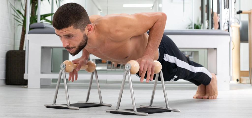 Man in front of Pilates Cadillac exercising on a Pilates Push-up device on Rubber Pads